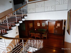 Una escalera con barandillas blancas ornamentales y peldaños de madera que descienden a un nivel inferior.