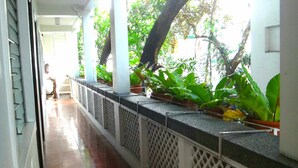 A corridor with a tiled floor, white railings, and potted plants. - Pension Natividad (Manila)