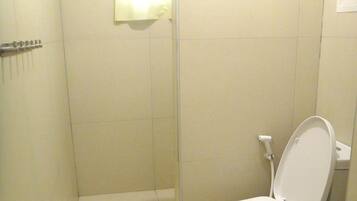 Une petite salle de bain compacte comprenant des toilettes, un espace douche et un porte-serviettes.