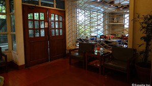 A dining area with a wooden door, a lattice window, and a table with chairs. - Pension Natividad (Manila)
