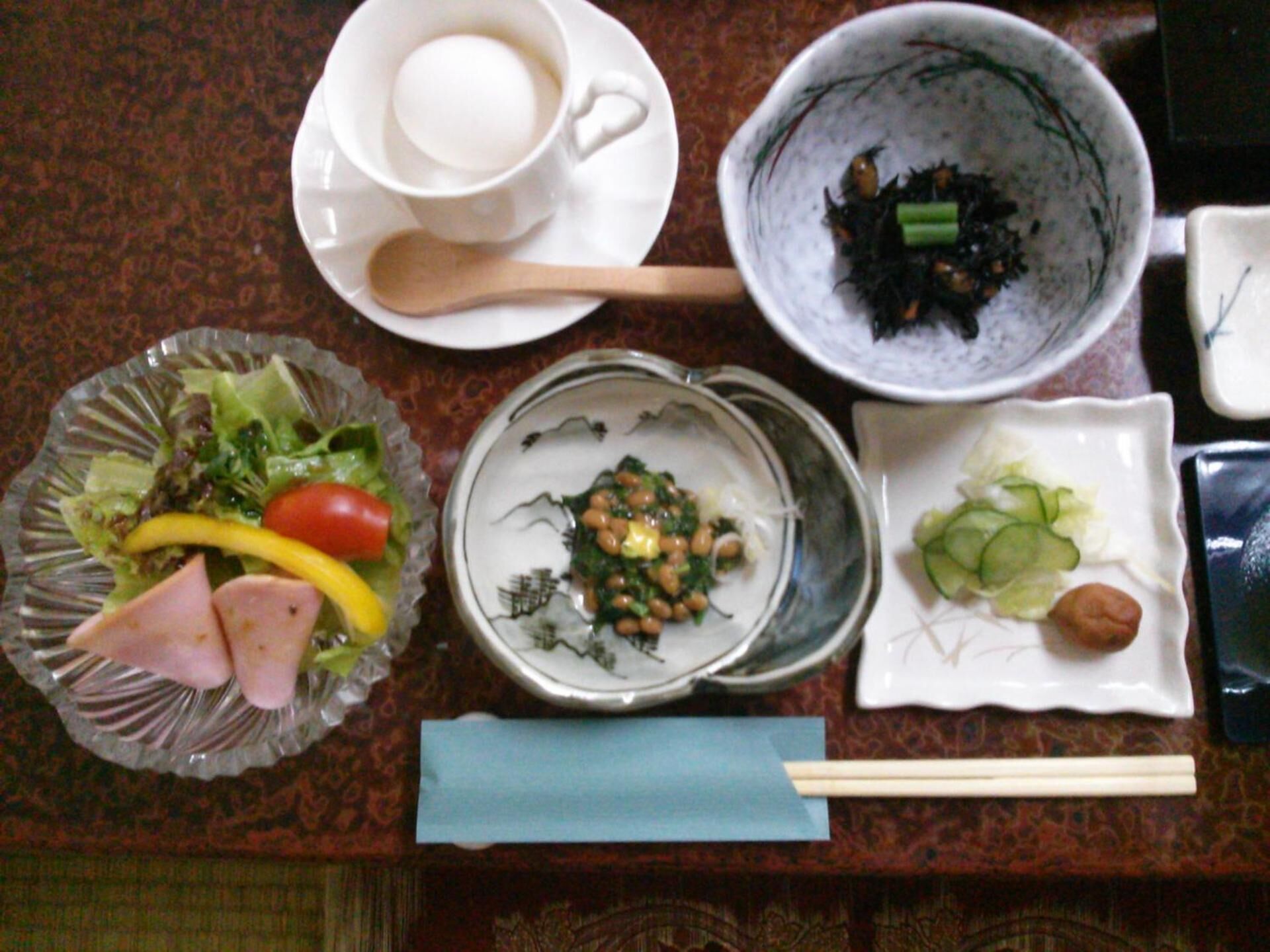 A table with various dishes including a salad, soup, and a bowl of seaweed.