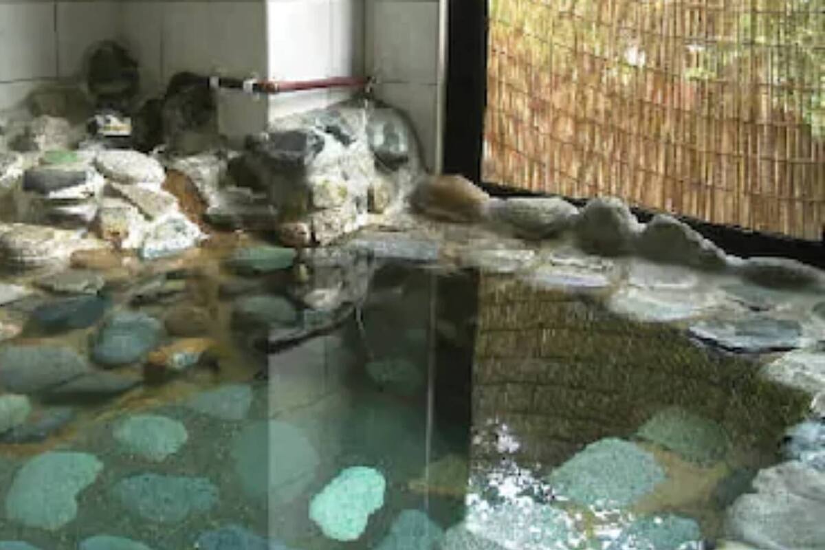A stone bath area with a bamboo screen, a stone ledge, and a wooden structure.