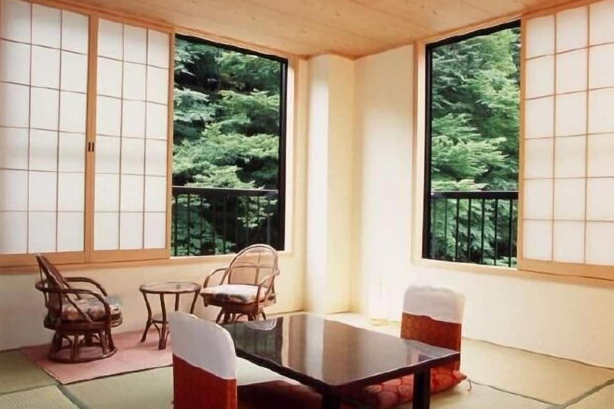A traditional Japanese room with tatami flooring, a low table, and chairs.