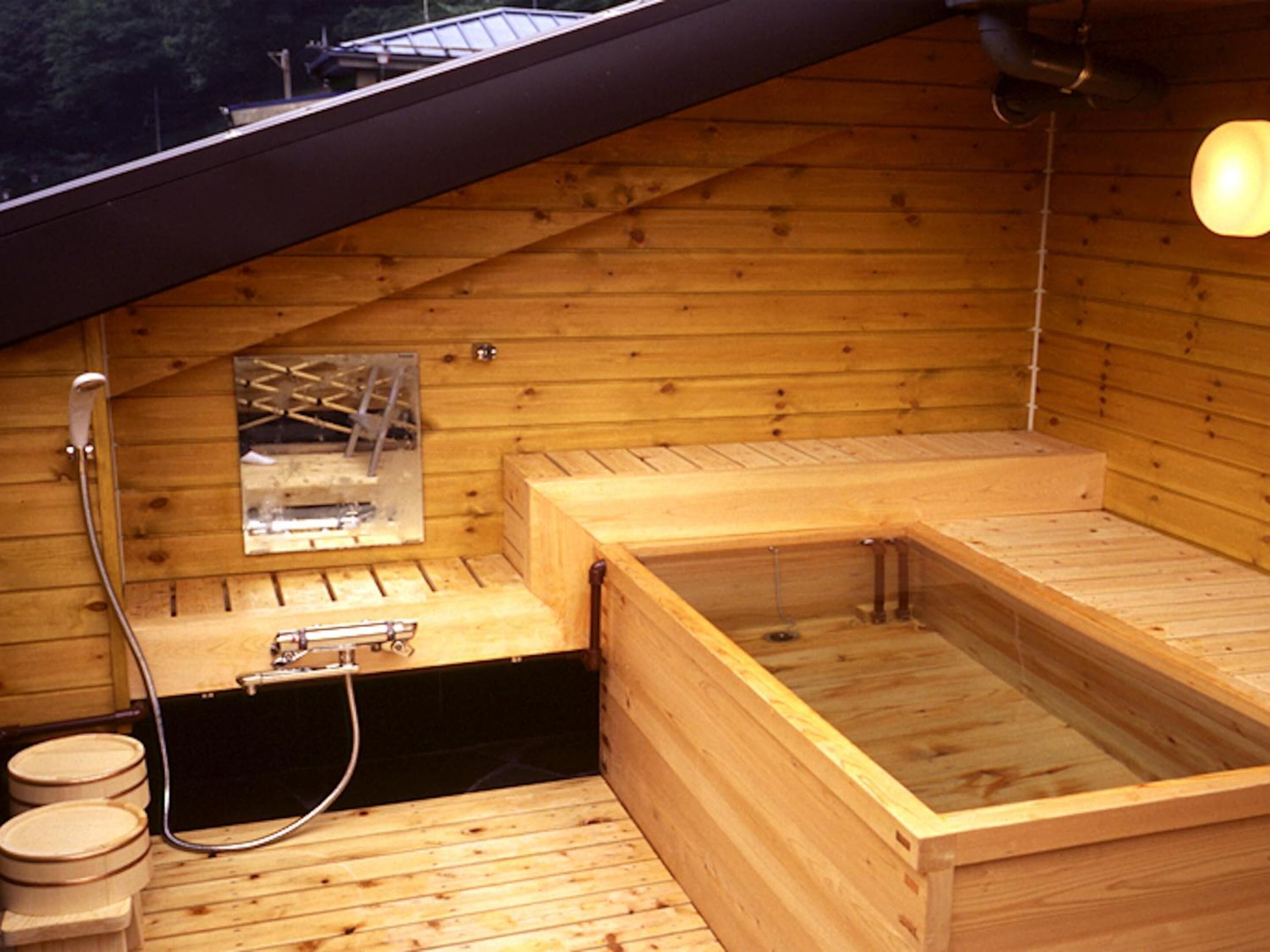 Una sauna de fusta amb una bassa i una zona de banyera d'hidromassatge separada, ambdues de fusta.
