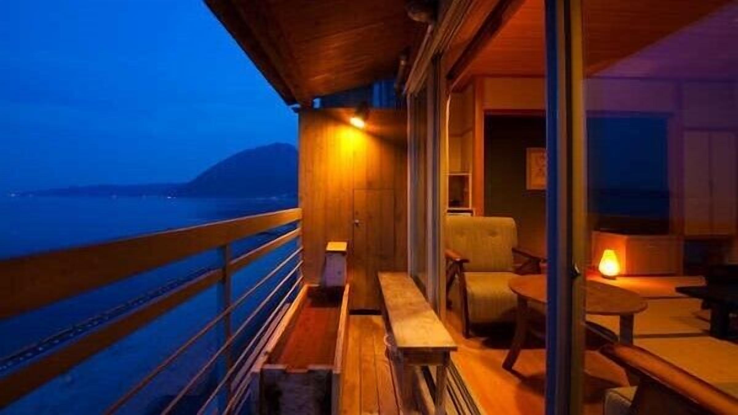 A balcony with a wooden railing, a bench, and a table with a lamp.