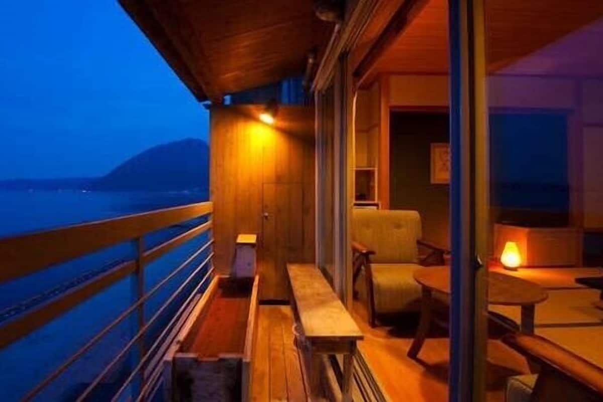 A balcony with a wooden railing, a bench, and a table with a lamp.