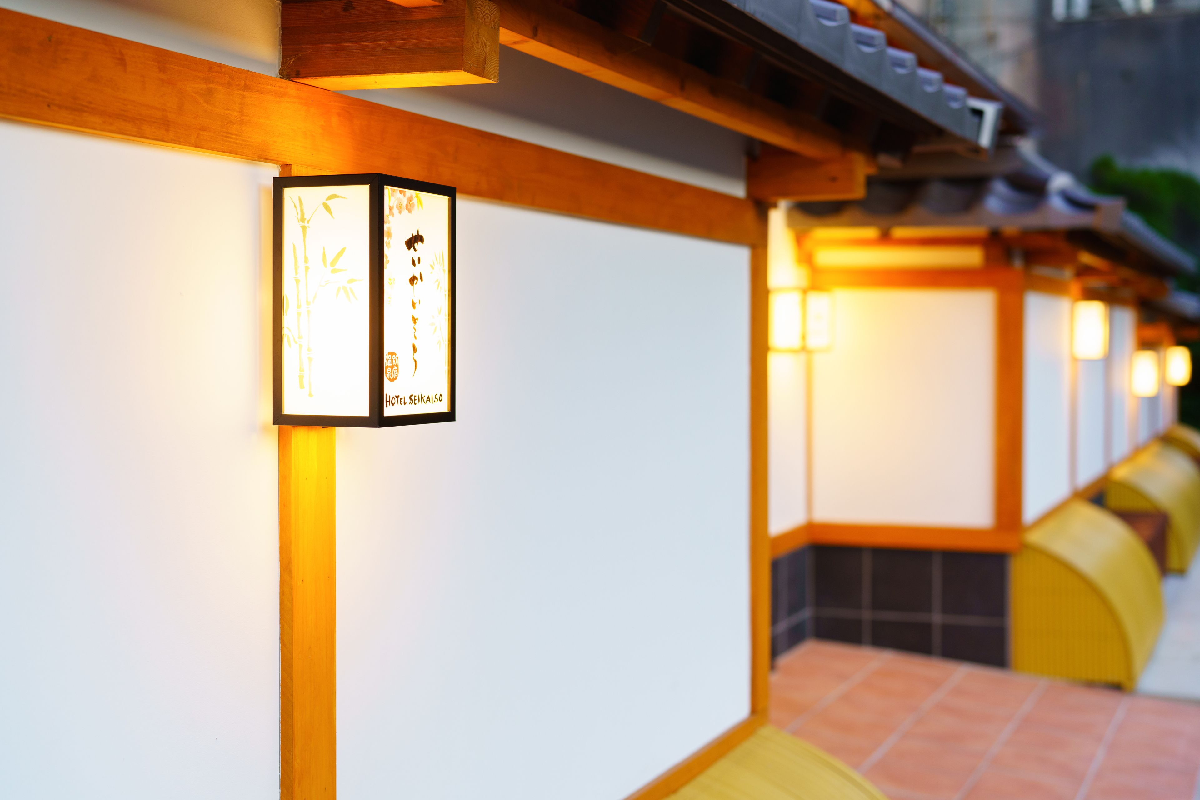 A row of traditional Japanese lanterns with calligraphy on the wall.
