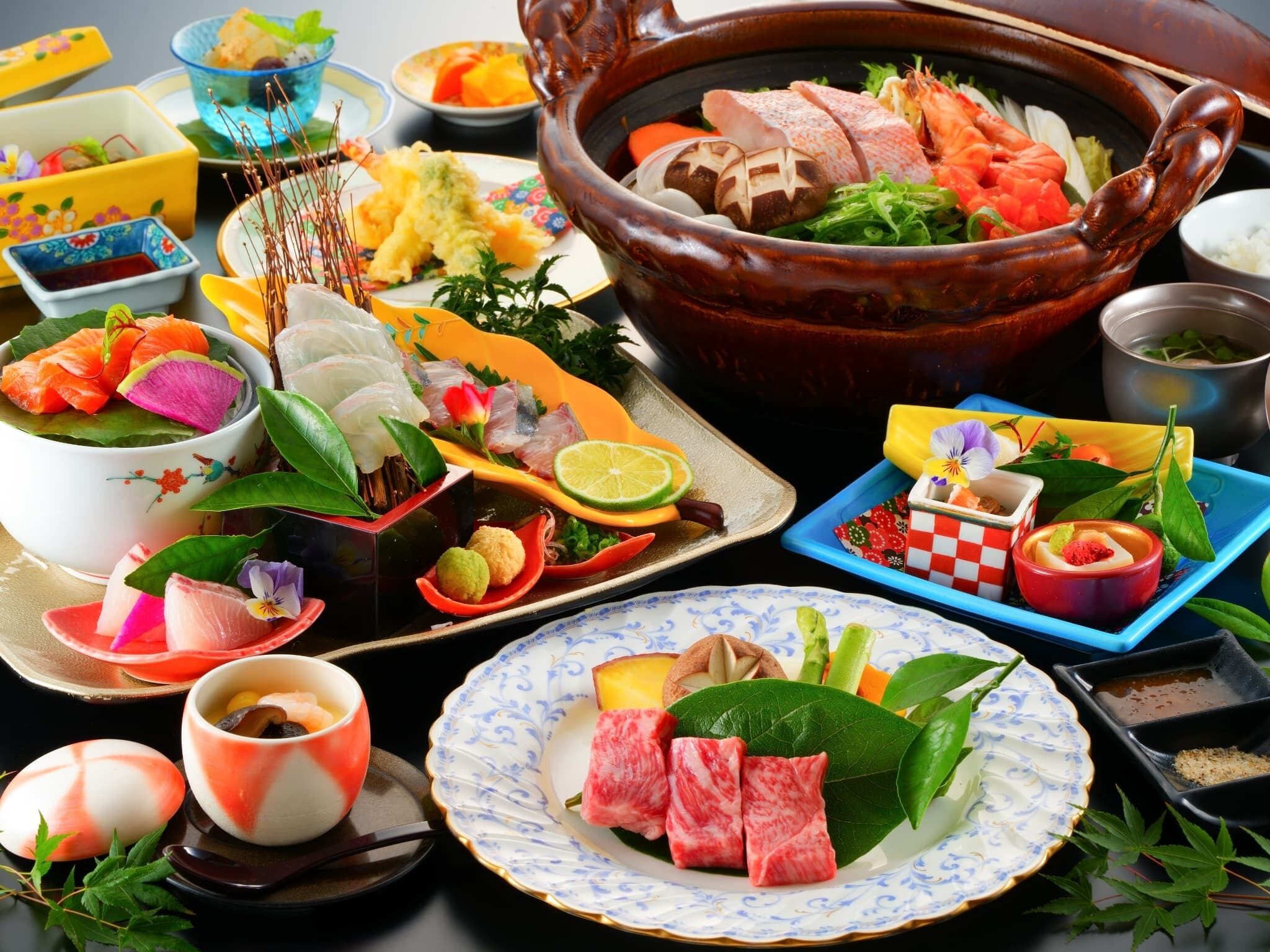 Forskellige retter og spiser, herunder sushi, sashimi og andre lækkerier, anrettet på et bord.