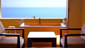 A room with a view of the ocean, a small sink, two chairs, and a table. - Tenku Yubo Seikaiso (Beppu)