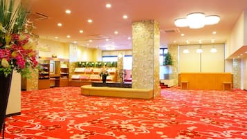 A spacious lobby with a red carpet, a reception desk, and a display of jewelry.