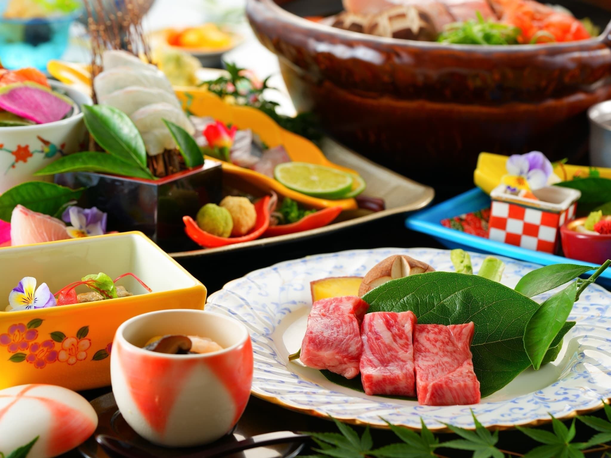A variety of food items and dishes on a table, including a bowl of soup, a plate with meat, and several small dishes with different ingredients.
