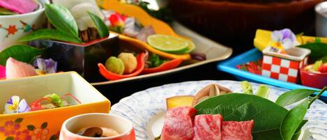 A variety of food items and dishes on a table, including a bowl of soup, a plate with meat, and several small dishes with different ingredients.