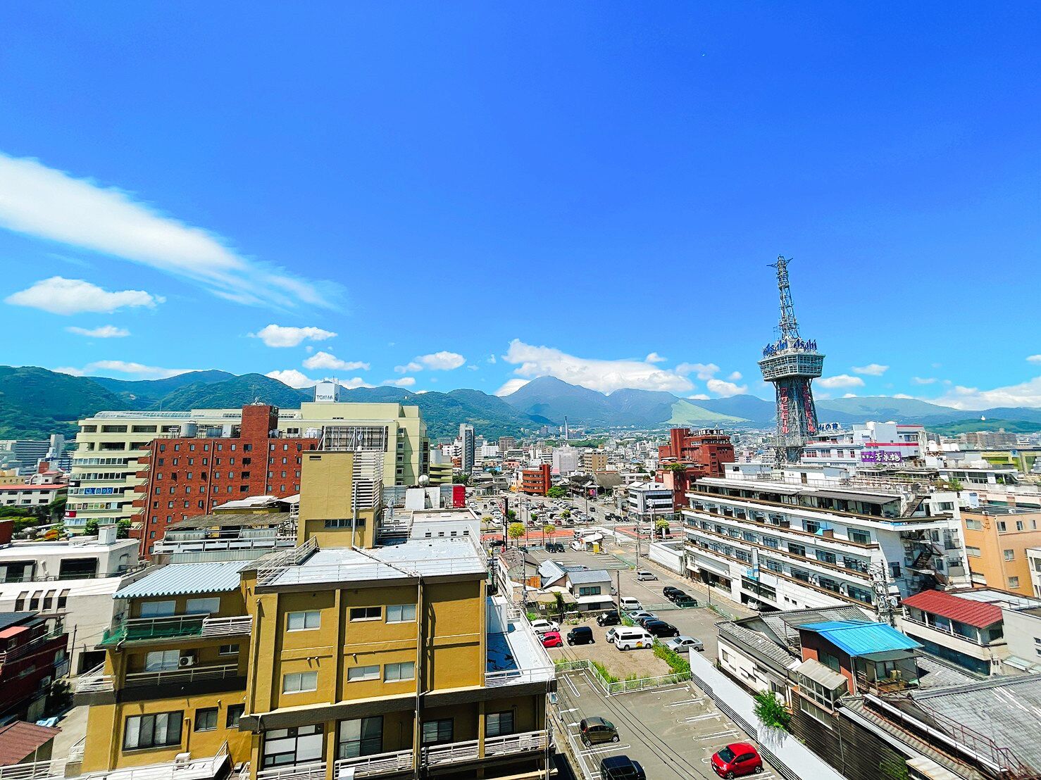 A cityscape with a prominent tower, various buildings, and a mountainous backdrop.
