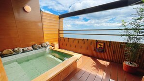 A wooden deck with a hot tub, a wooden wall, and a view of the sea. - Tenku Yubo Seikaiso (Beppu)