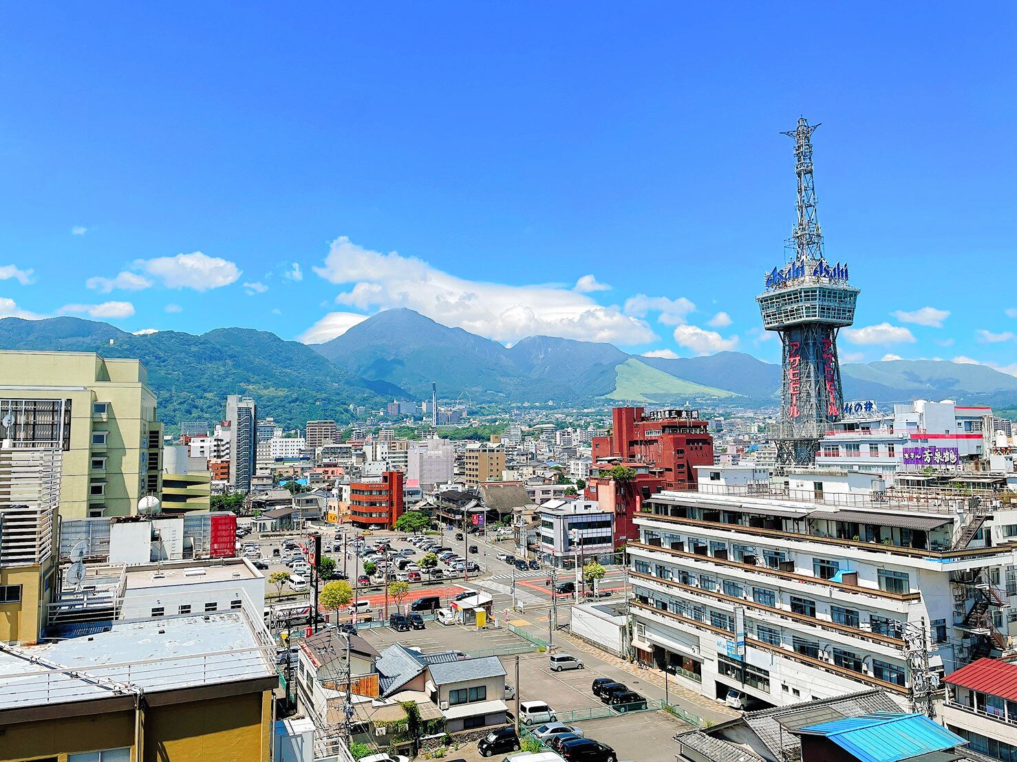 A cityscape with a prominent tower, various buildings, and mountains in the background.