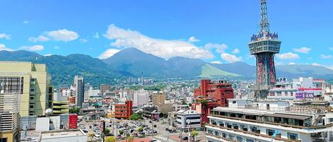 A cityscape with a prominent tower, various buildings, and mountains in the background.