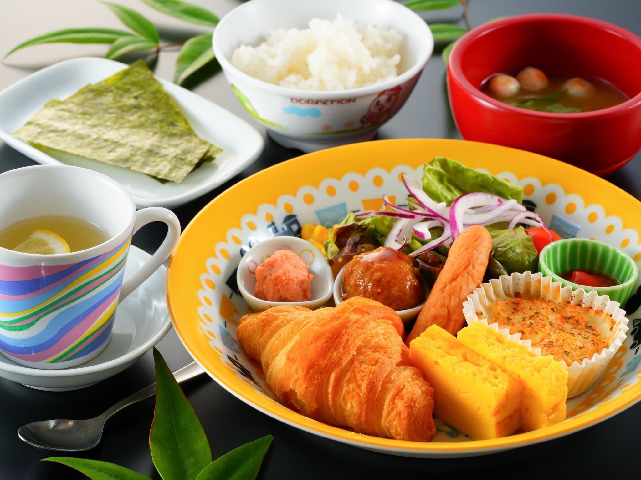 A plate with croissants, cheese, salad, and soup.