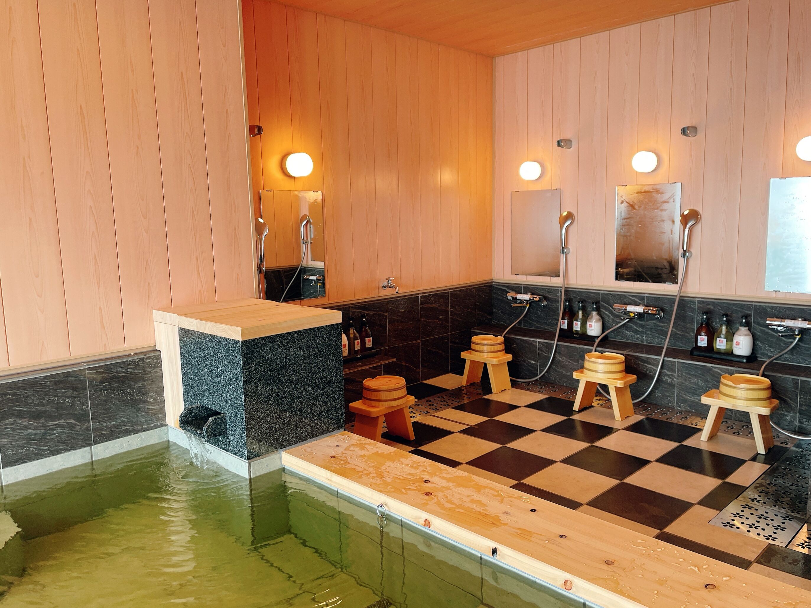 A sauna with wooden benches, a marble counter, and a checkered floor.