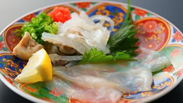 A plate with various seafood items, including fish and possibly shrimp, garnished with lemon and herbs.