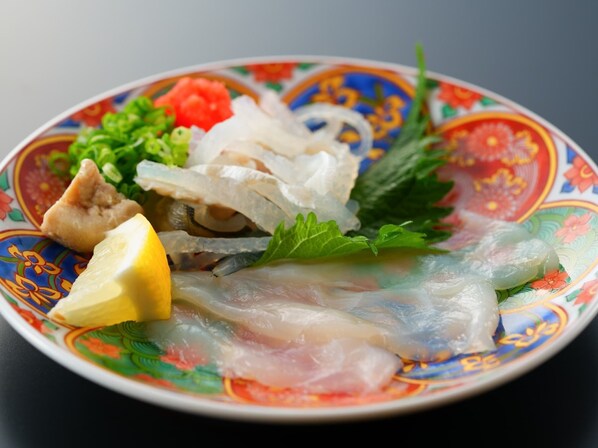A plate with various seafood items, including fish and possibly shrimp, garnished with lemon and herbs.