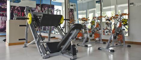 Un gimnasio con diverso equipo de ejercicio, incluyendo cintas de correr y máquinas de pesas.