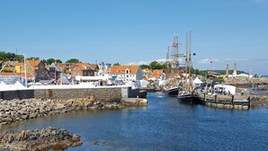 Ein Hafen mit Booten, einer Steinmauer und Gebäuden mit roten Dächern.