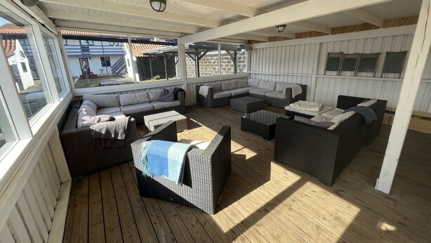 Ein überdachter Außenbereich mit Korbmöbeln und einer Holzterrasse.