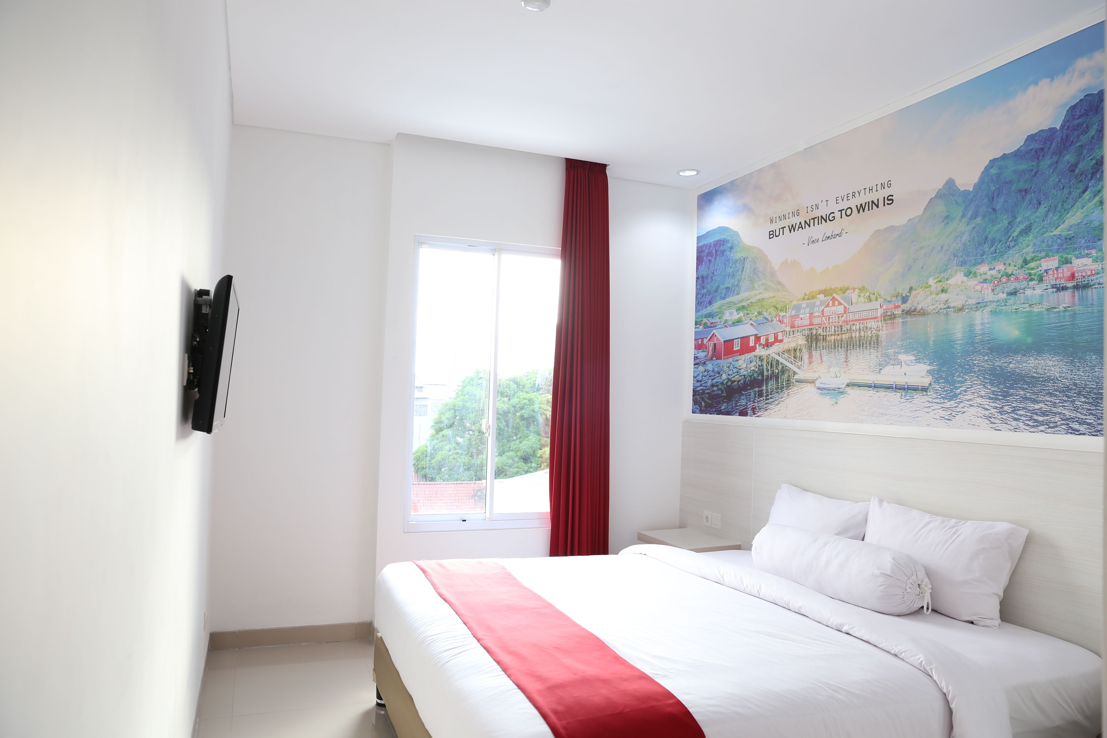 Una habitación de hotel con una cama grande, una ventana con cortinas rojas y un mural panorámico en la pared.