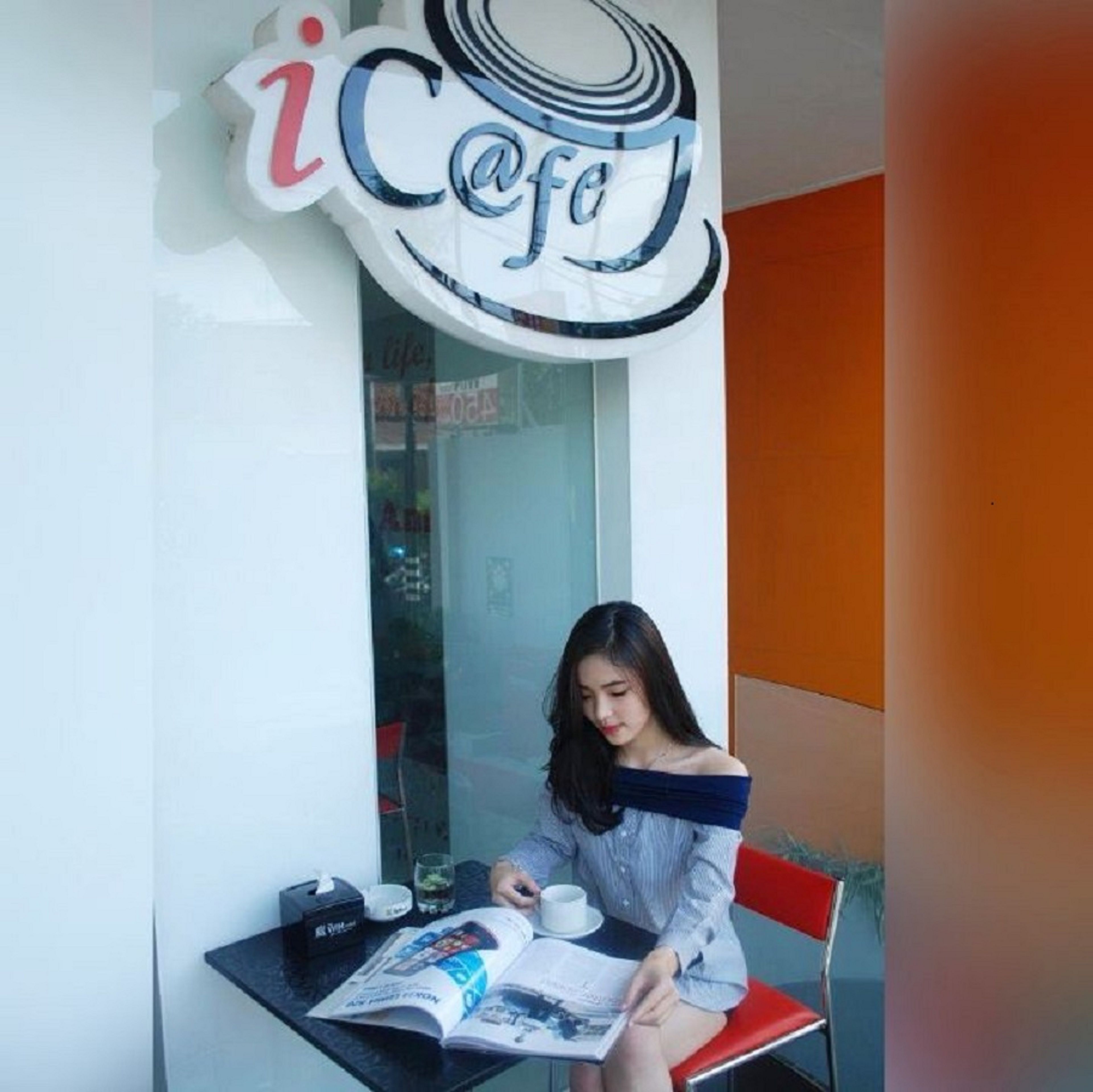 Una persona sentada a una mesa con una revista, una taza y una caja de pañuelos.