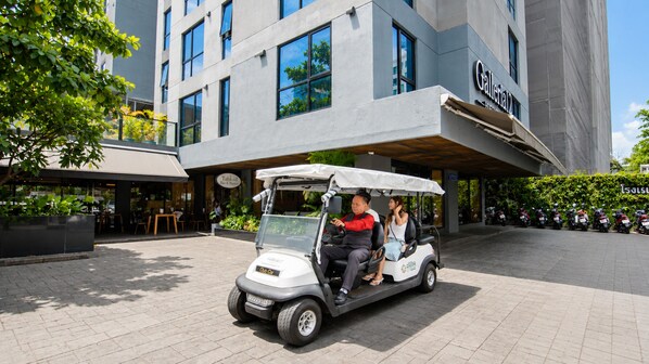 Un edificio moderno con entrada cubierta, un carrito de golf y una fila de scooters estacionados.