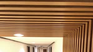A long, narrow hallway with a striped ceiling and walls, leading to a door at the end. - At Bangkok Hotel (Bangkok)