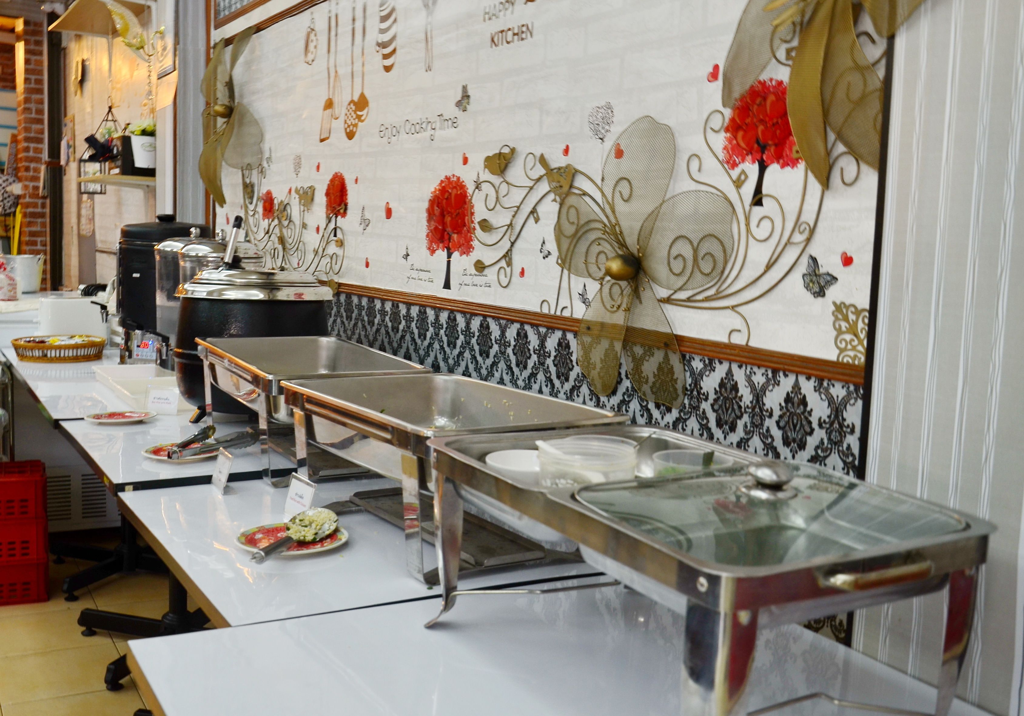 A buffet setup with multiple serving stations and a decorative wall with floral patterns.