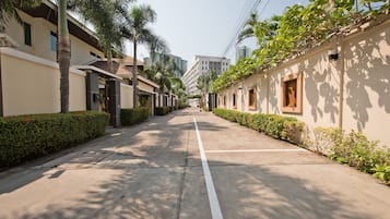 A residential street with modern houses, palm trees, and a clear sky.