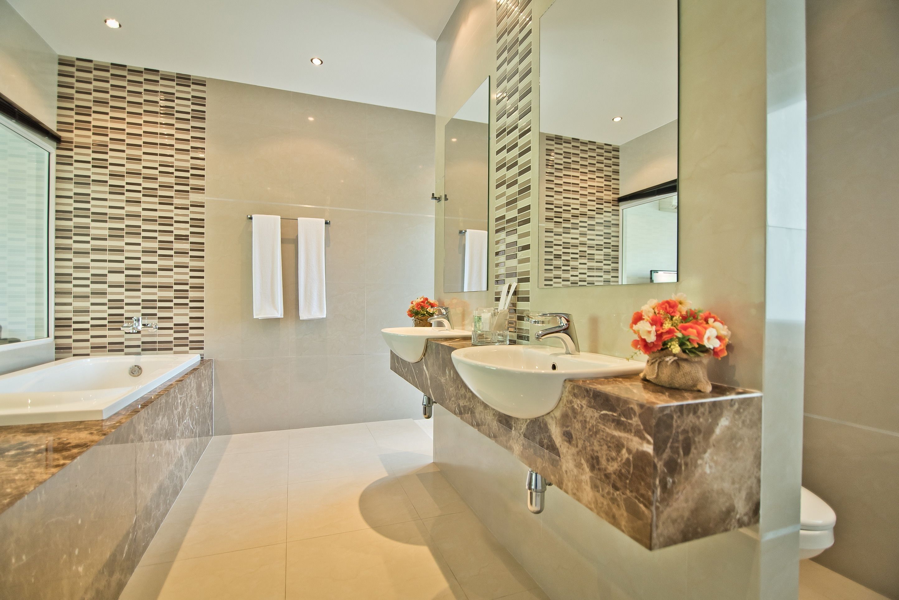 Un bagno moderno con due lavabi, una vasca e uno specchio grande.