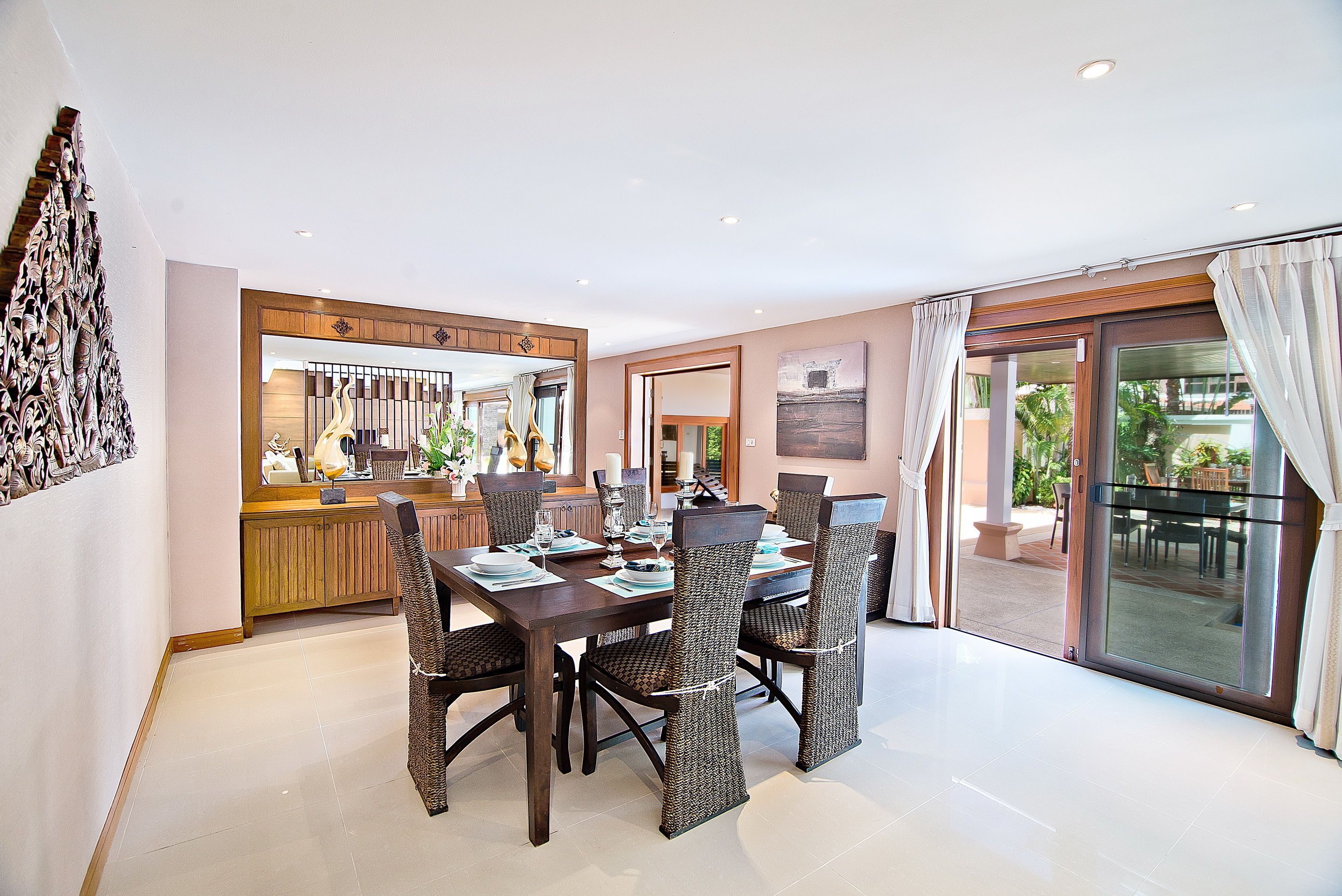 A dining area with a large table, chairs, and a view of the outdoors through a glass door.