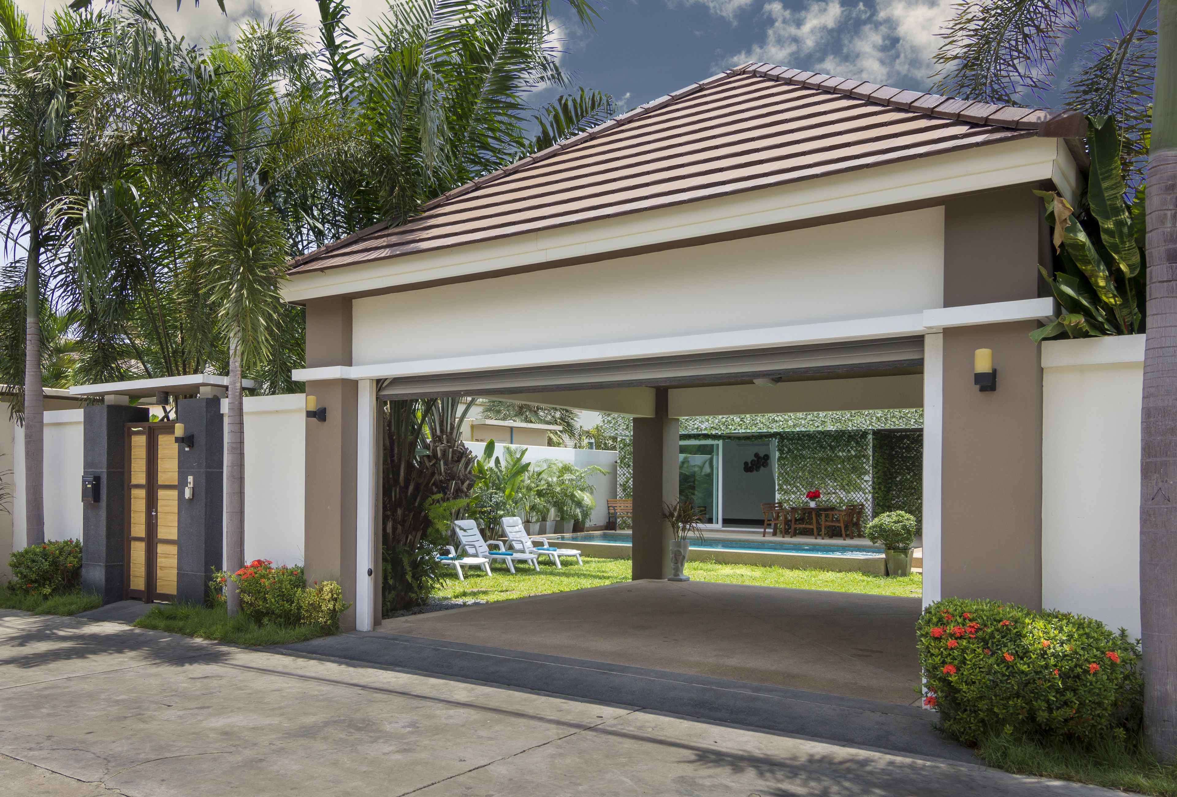 Una casa moderna con entrada cubierta, piscina y jardín cuidado.