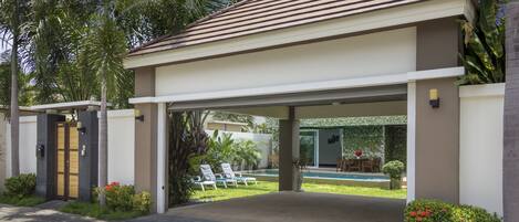 Una casa moderna con entrada cubierta, piscina y jardín cuidado.