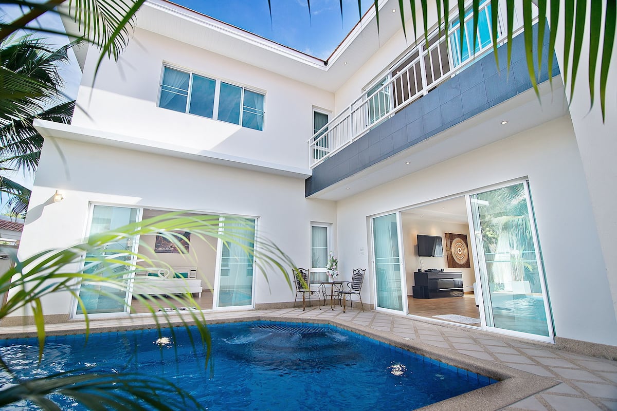 Una casa moderna de dos pisos con piscina, balcón y comedor.