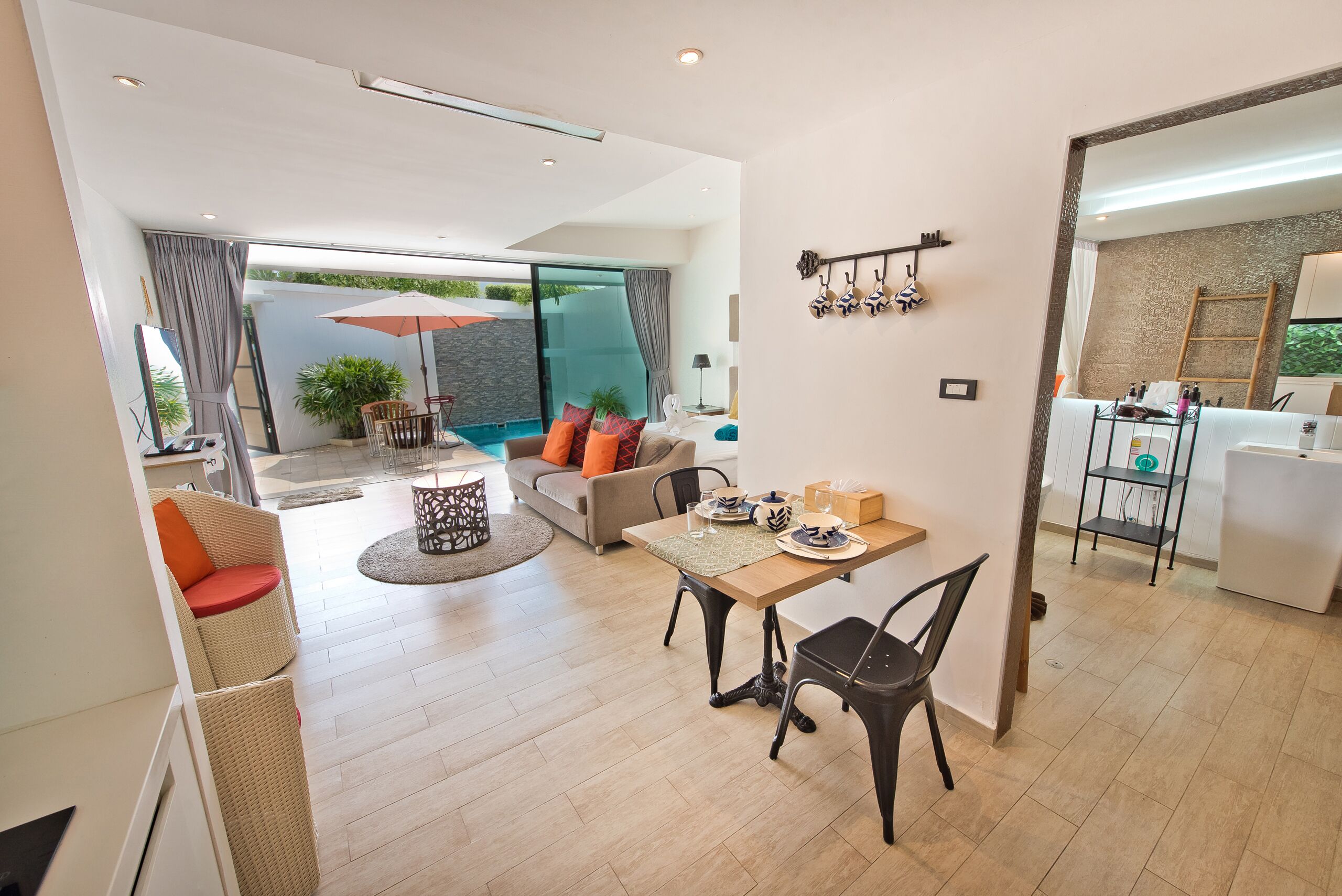 A modern living room with a dining area, a sofa, a coffee table, and a view of a swimming pool.