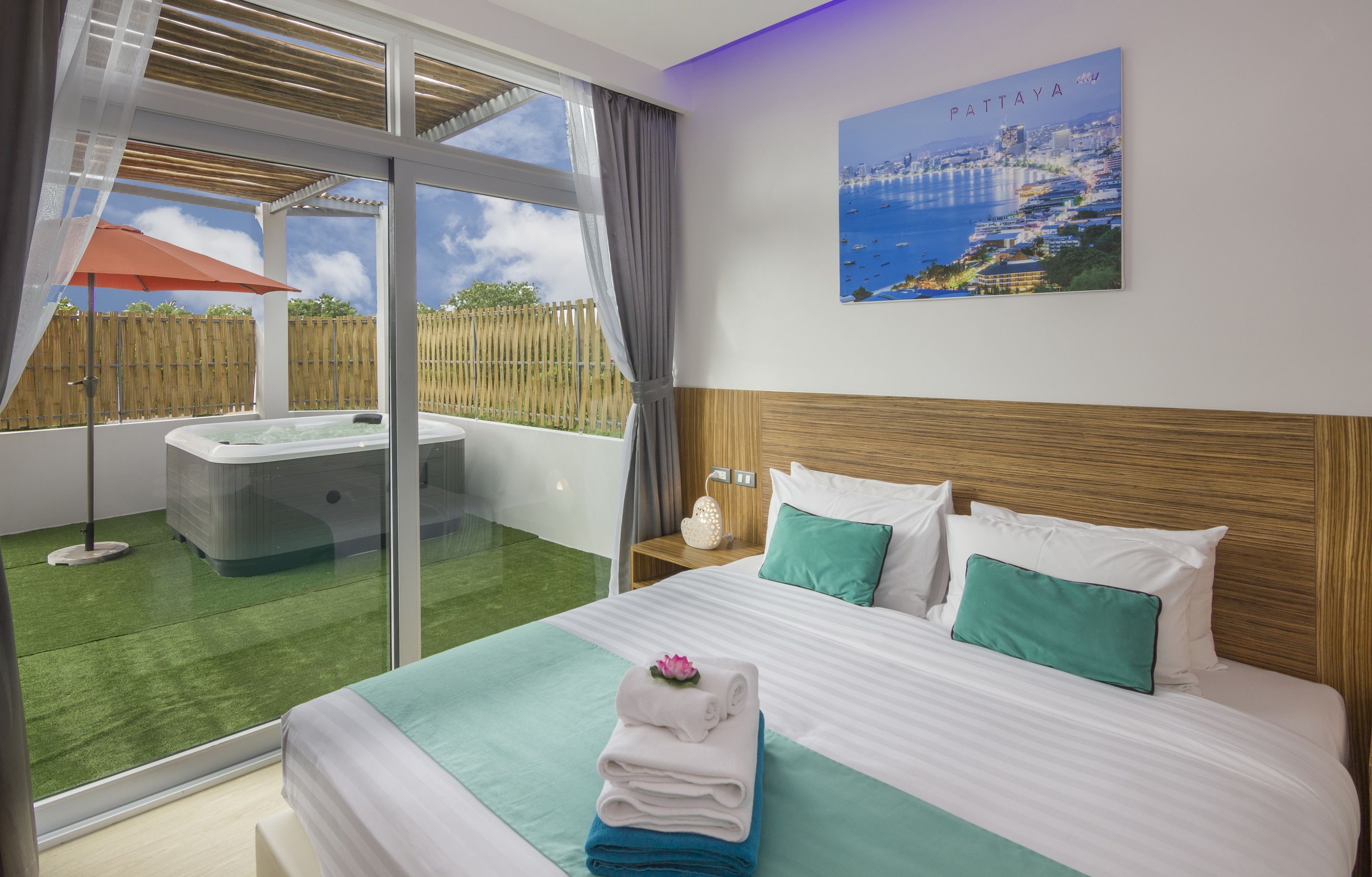 Ein Hotelzimmer mit Bett, Blick auf die Stadtlandschaft, Whirlpool und Balkon mit Holzlattenzaun.
