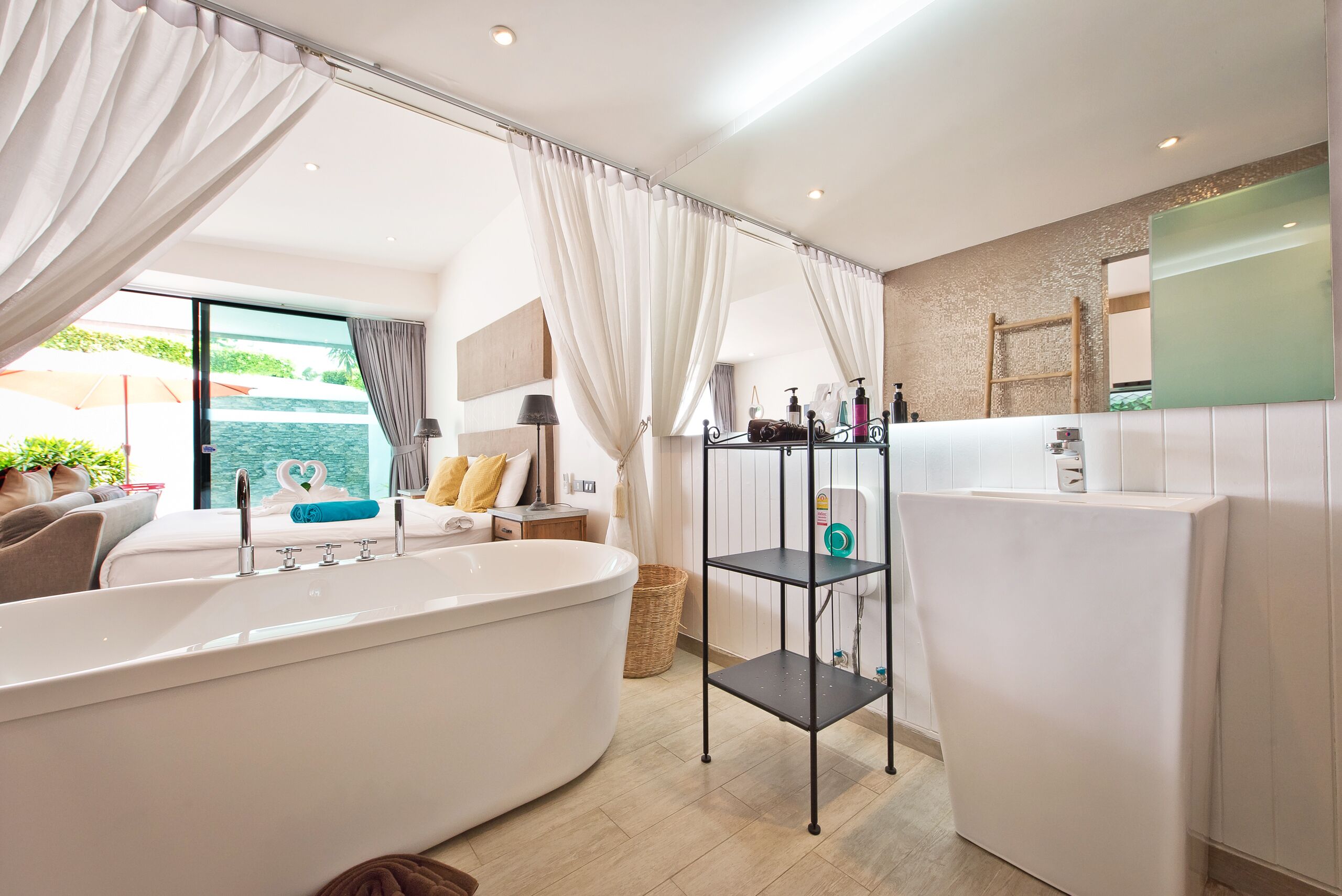A modern bathroom with a freestanding bathtub, a vanity with a mirror, and a shelf with toiletries.