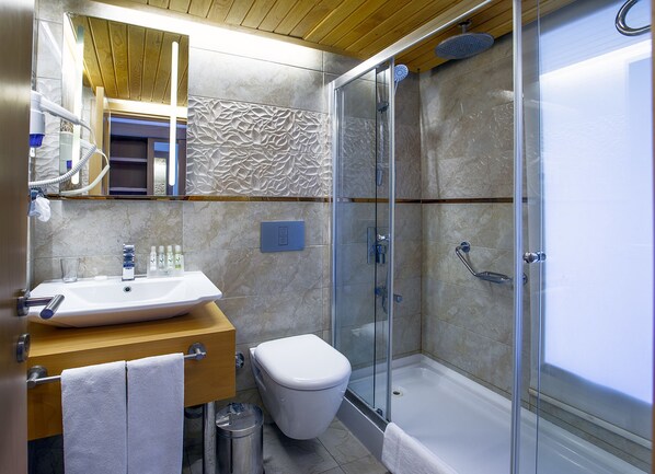 Un baño moderno con ducha de vidrio, lavamanos blanco y retrete.