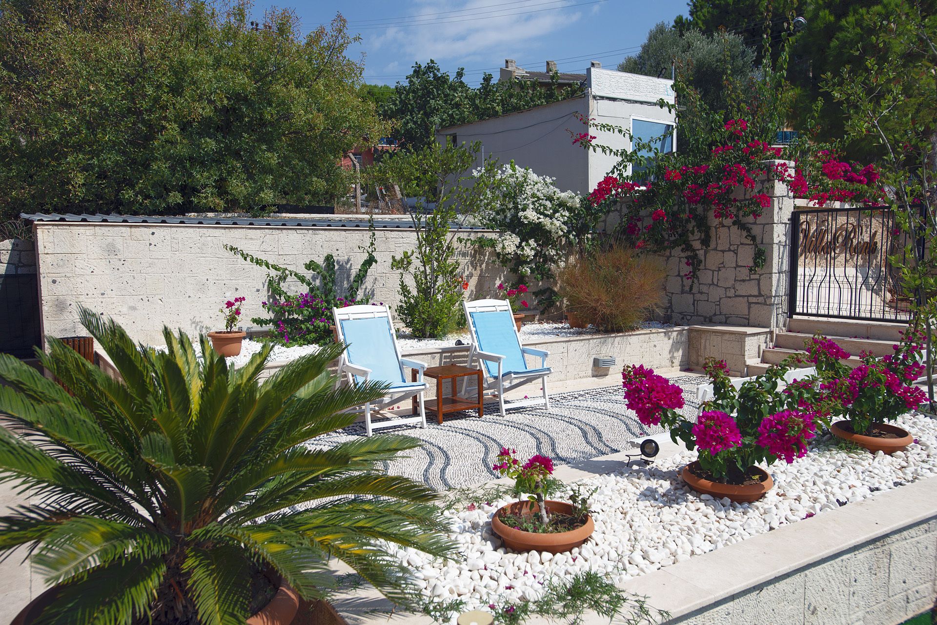 A patio with two lounge chairs, a small table, and potted plants.