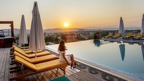 A poolside area with lounge chairs and umbrellas, overlooking a cityscape at sunset. - Alacati Villa Renk (Cesme)