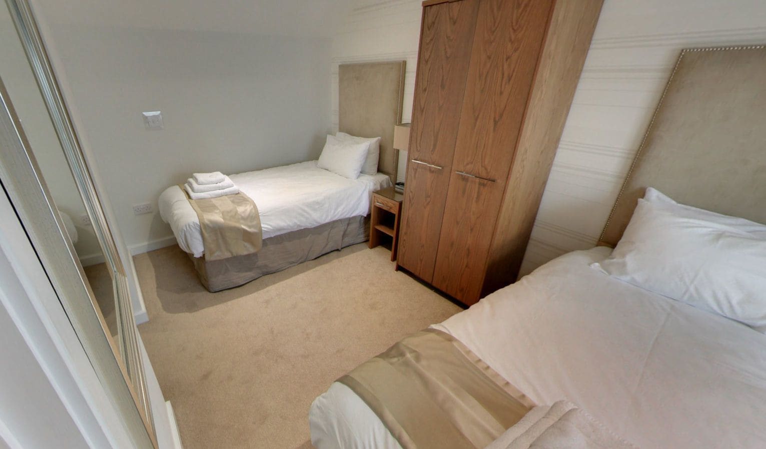 Ein Schlafzimmer mit zwei Betten, einem Holzschrank und einem kleinen Nachttisch.