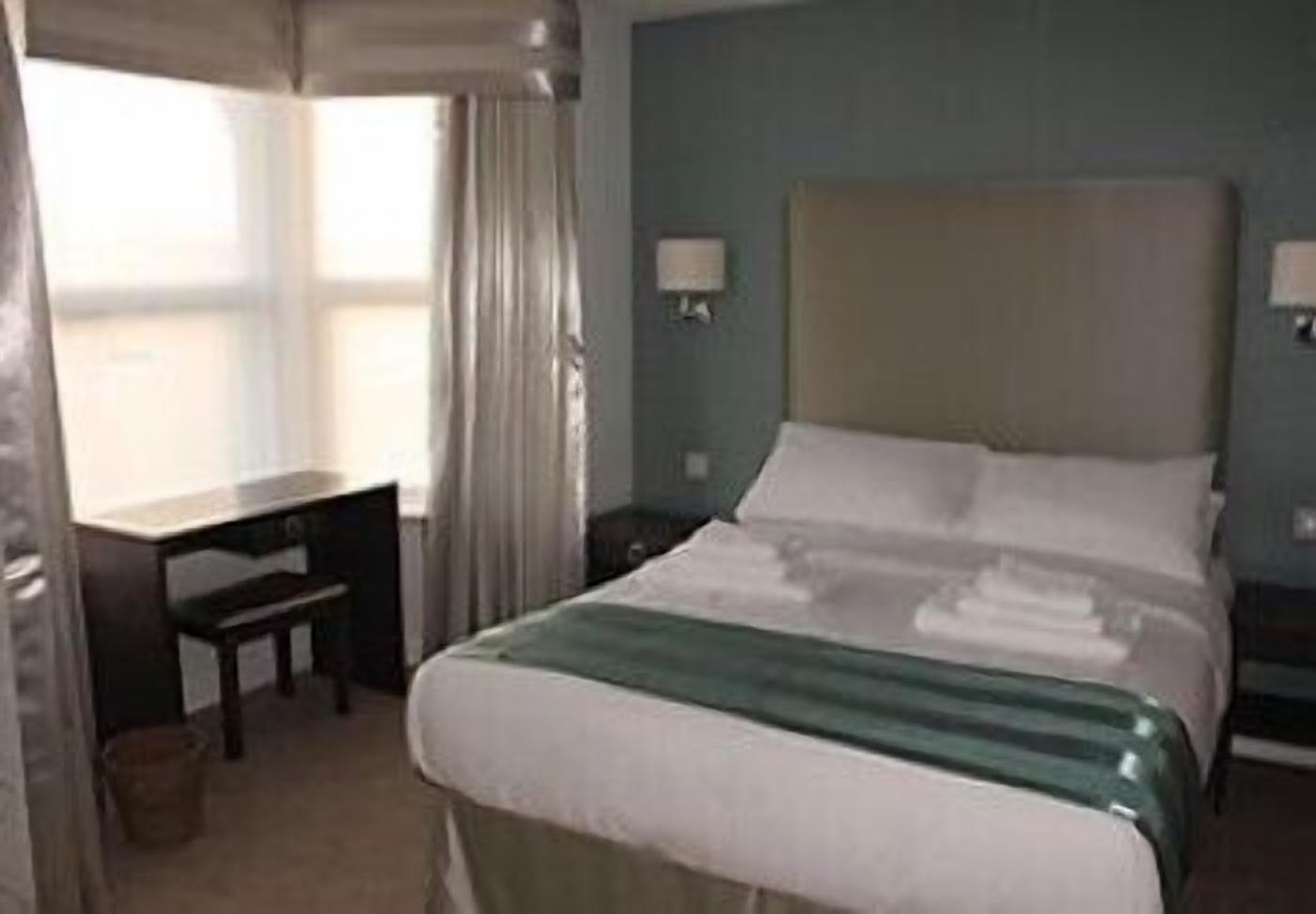 A hotel room with a bed, a desk, and a chair.