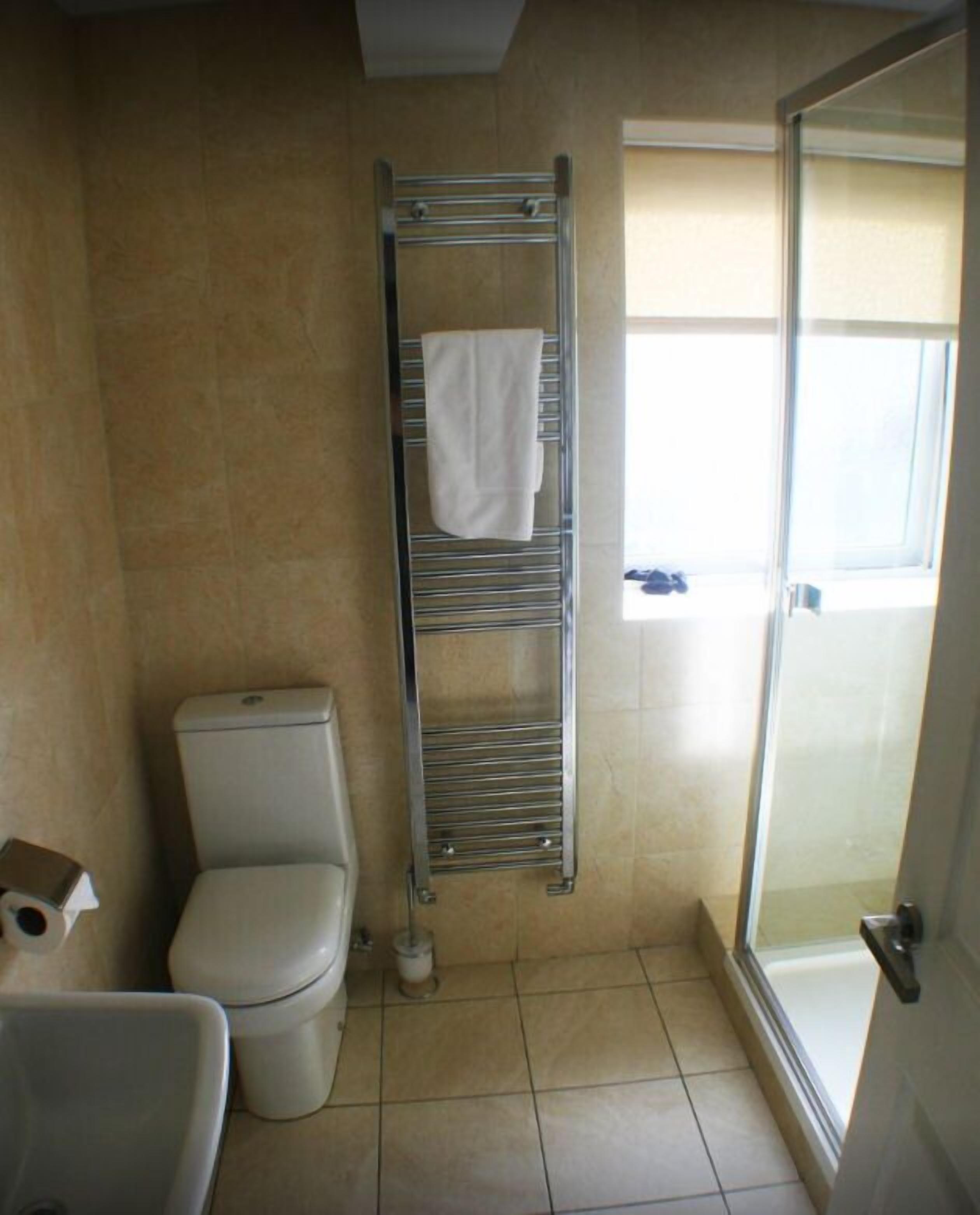 A bathroom with a toilet, a towel rack, and a shower area.