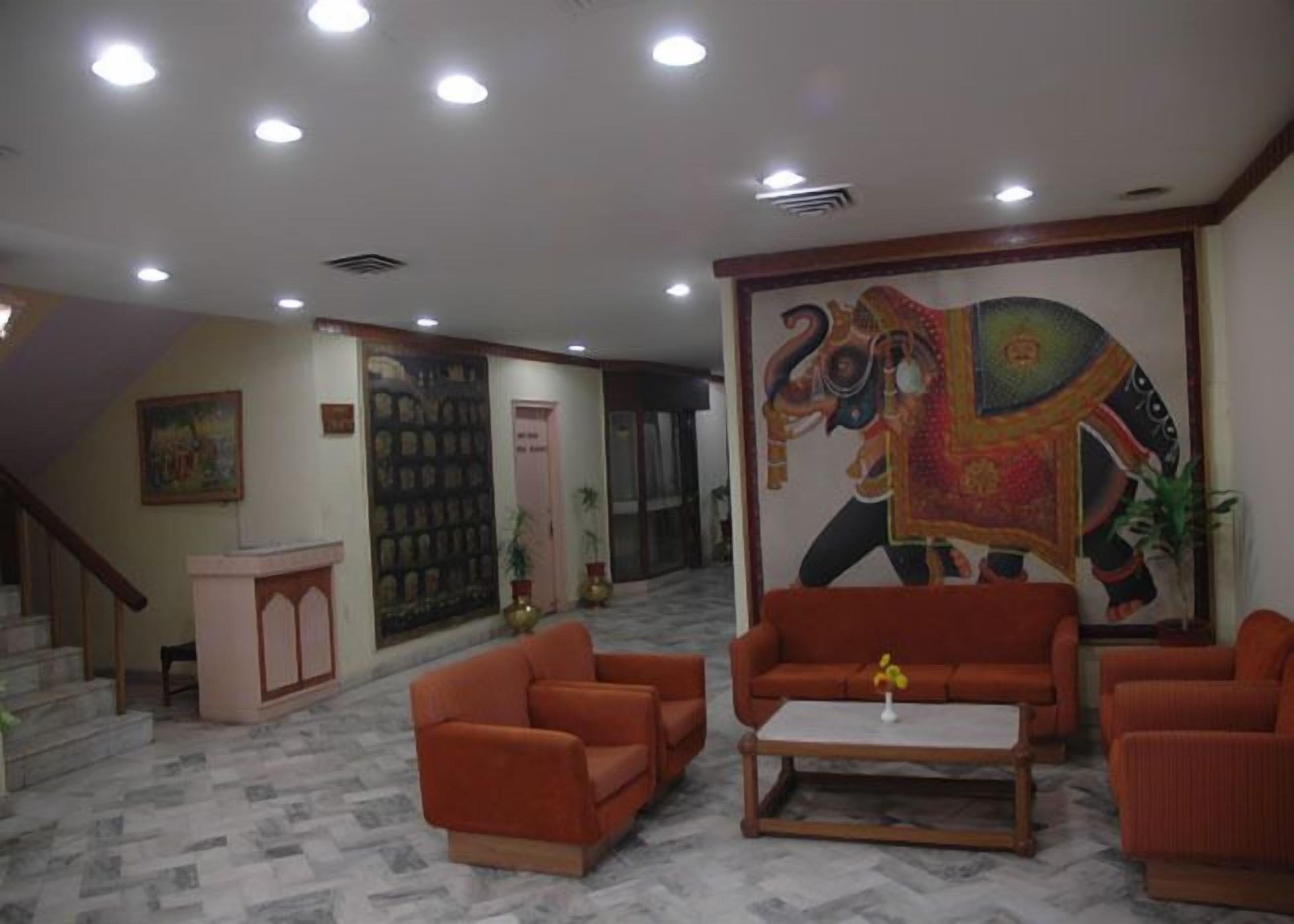 A lobby with a large mural of an elephant, a staircase, and orange sofas.