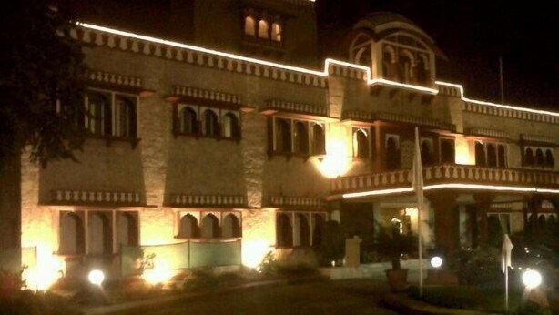 A large building with multiple arches and a balcony, illuminated at night. - Hotel Jaipur Ashok (Jaipur)