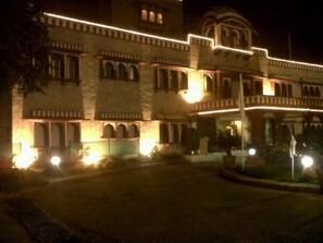 A large building with multiple arches and a balcony, illuminated at night. - Hotel Jaipur Ashok (Jaipur)
